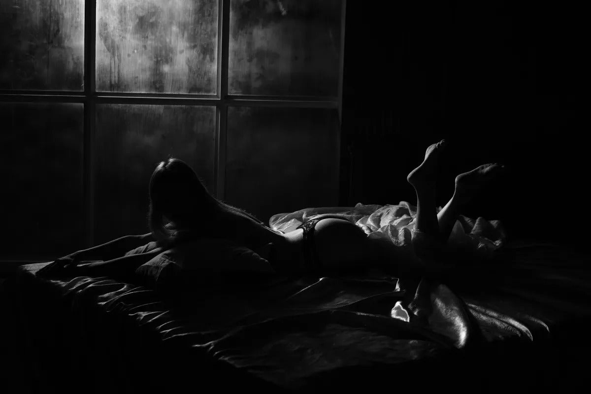 femme allongée sur un lit dans la pénombre
