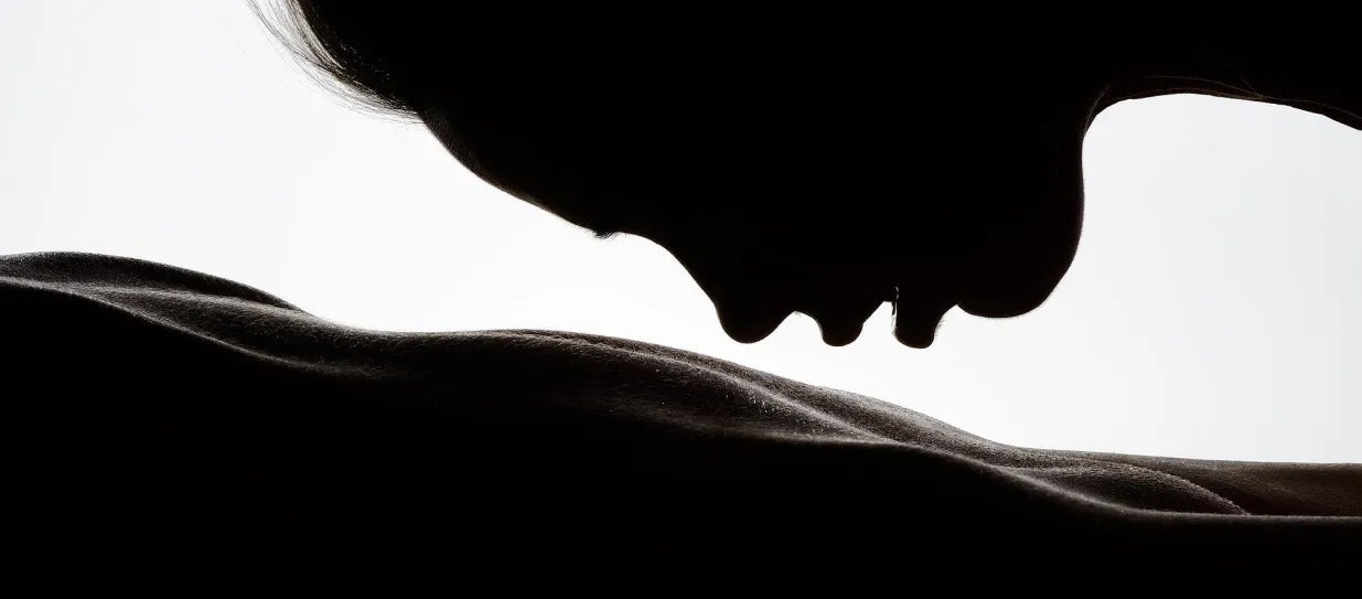 une femme qui s'apprête à faire un bisou sur le dos de quelqu'un allongé