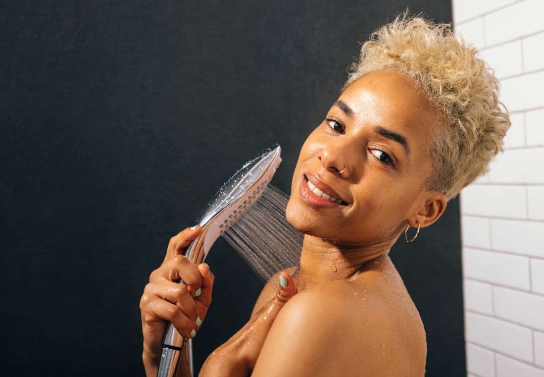 une femme qui prend une douche avec le pommeau Wave