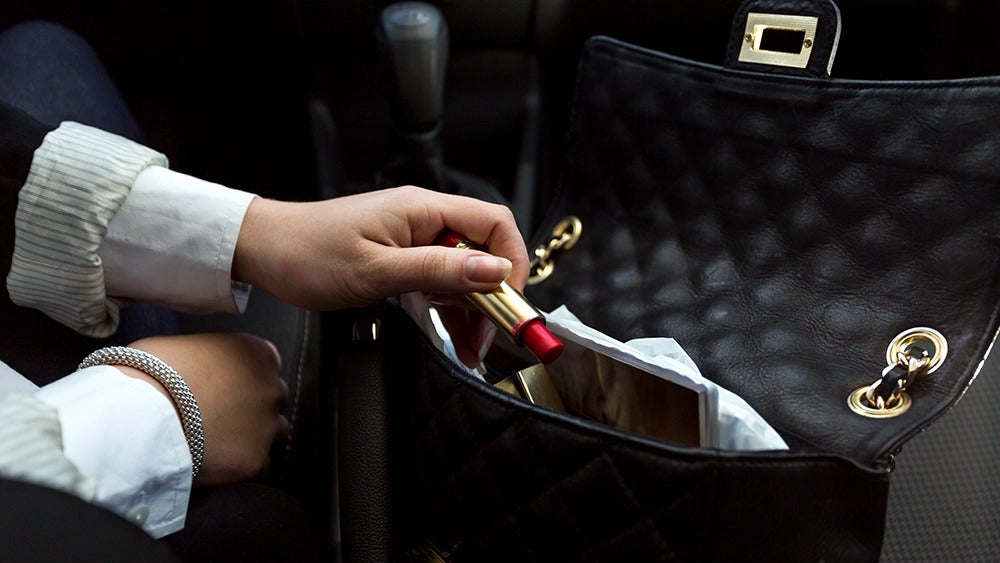 une femme prend un rouge à lèvres dans son sac à main.