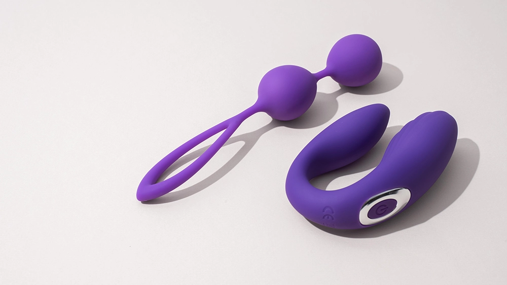 Deux sextoys en silicone violet sur fond clair, adaptés pour débuter : boules de geisha et stimulateur de couple.